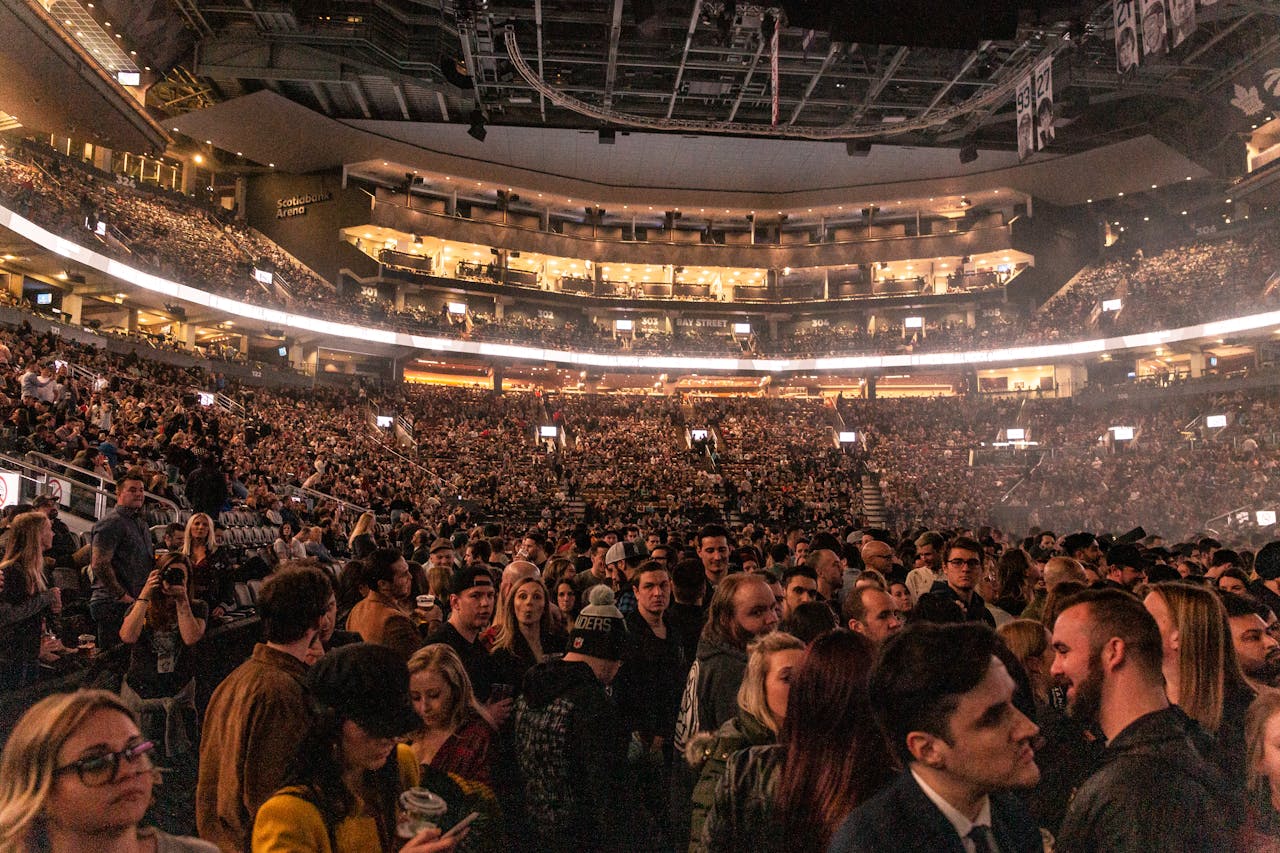 Home A large crowd gathers in an indoor arena for a lively event, surrounded by bright lights.